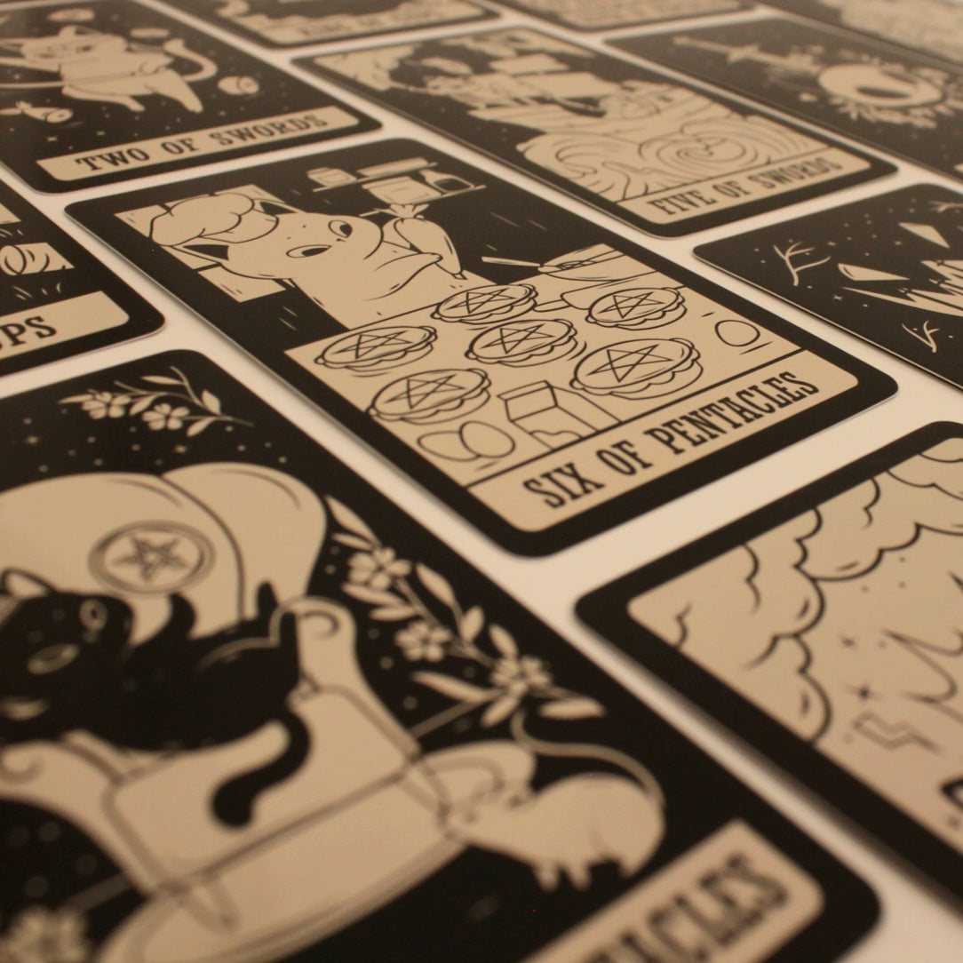 Zbliżenie na karty tarota przedstawiające różne postaci zwierząt w minimalistycznym stylu. Na pierwszym planie karta "Six of Pentacles" z ilustracją świnki przy stole.