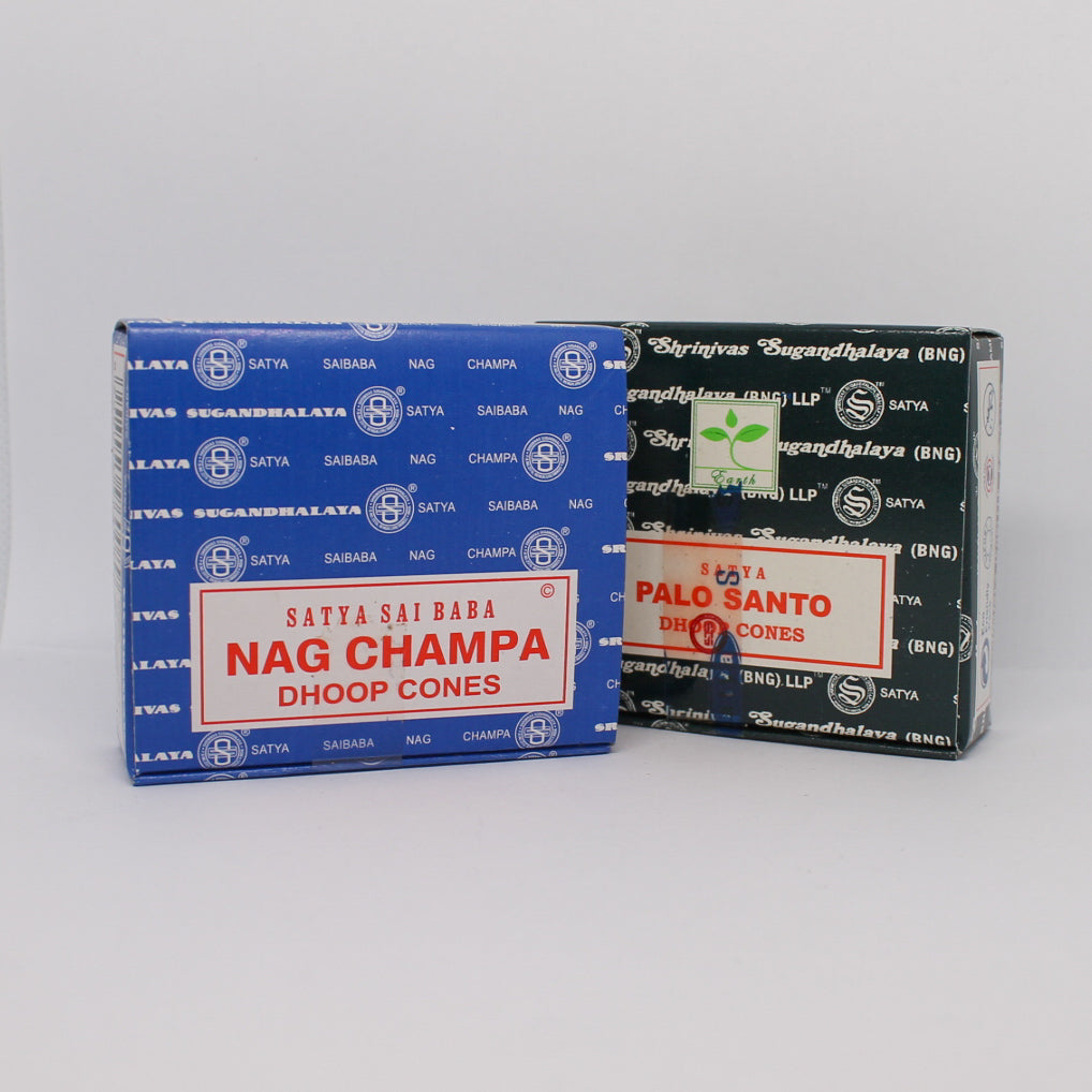 Dwa pudełka kadzideł stożkowych: Satya Sai Baba Nag Champa (niebieskie opakowanie) i Satya Palo Santo (czarne opakowanie). Obydwa mają białe etykiety z czerwonym napisem.