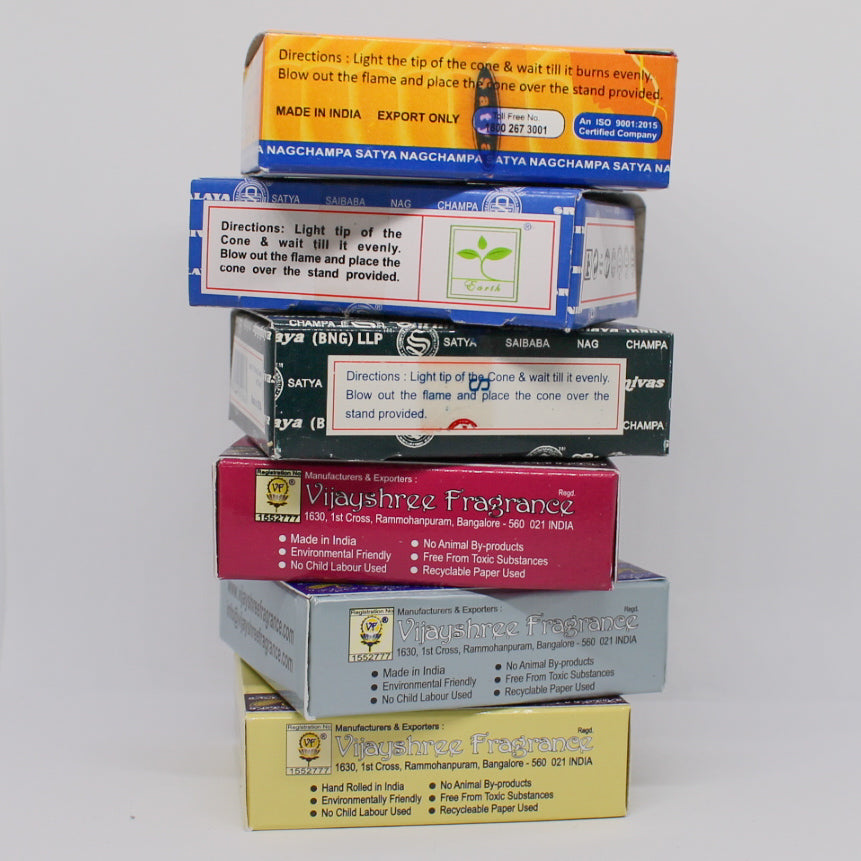 Stos sześciu pudełek kadzideł, ułożonych jedno na drugim. Na widocznych etykietach znajdują się instrukcje dotyczące użytkowania, nazwy marek oraz różne kolory opakowań.