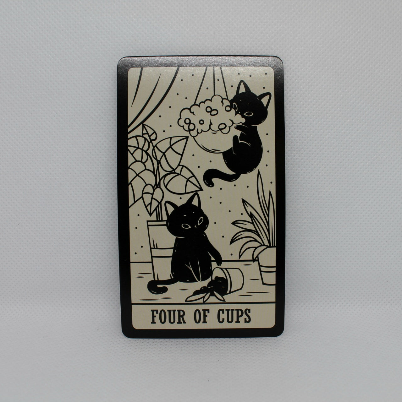 Karta tarota "Four of Cups" z dwoma kotami bawiącymi się w pomieszczeniu pełnym roślin.