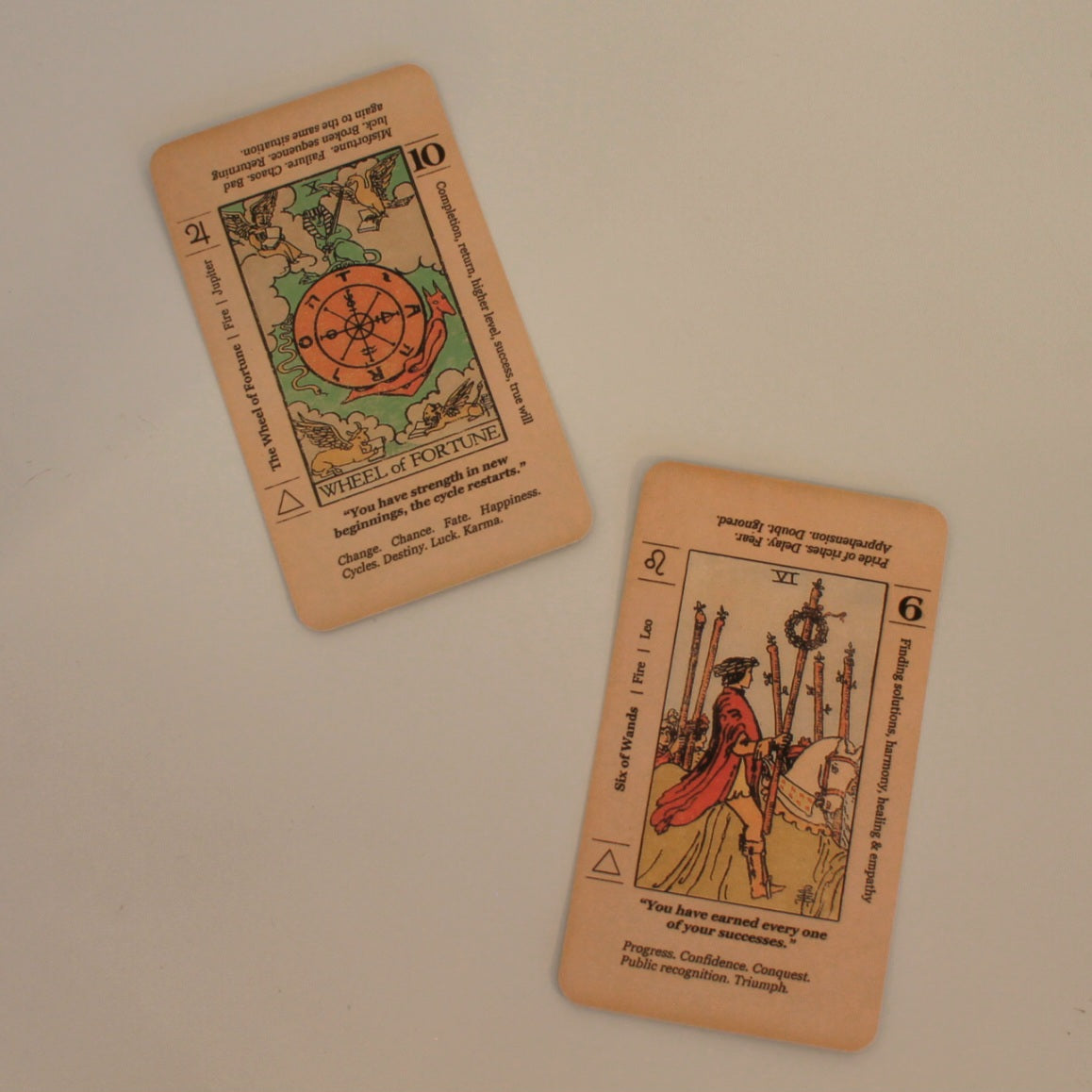 Zdjęcie przedstawia dwie karty tarota z talii "Meaning Tarot", ułożone na jasnym tle. Widoczne są szczegóły ilustracji oraz opisy interpretacji kart, w tym ich znaczenie w odwróconej pozycji.