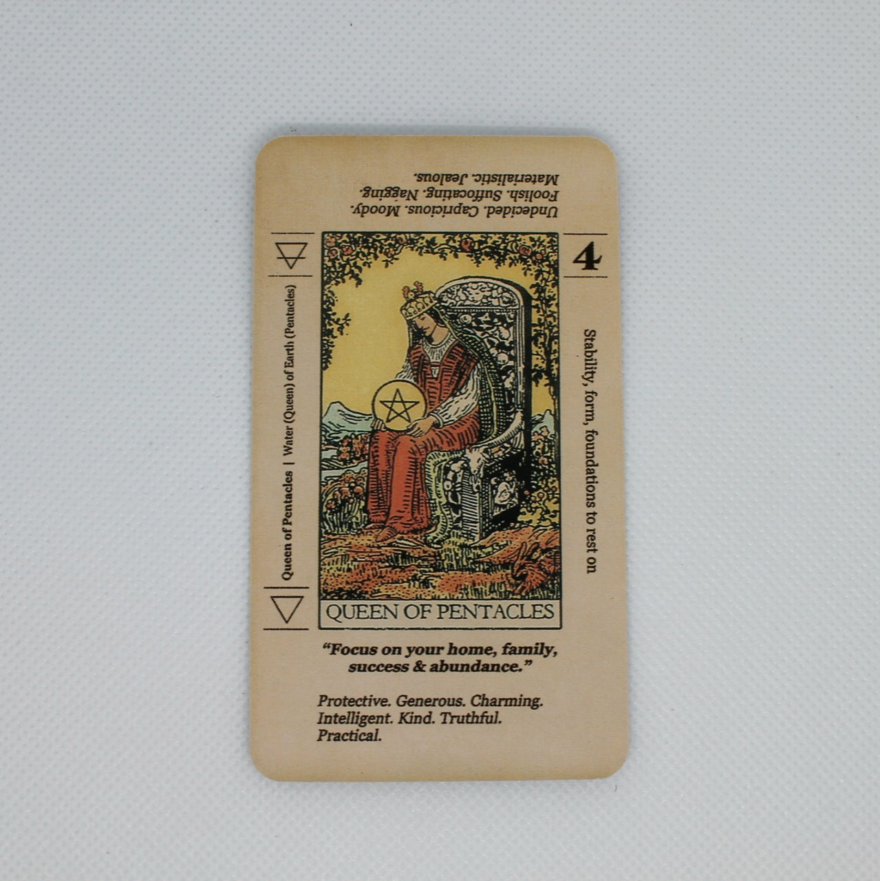 Zdjęcie przedstawia kartę "Queen of Pentacles" (Królowa Pentakli) z talii tarota "Meaning Tarot". Karta zawiera klasyczną ilustrację oraz dodatkowe opisy znaczeń i interpretacji.