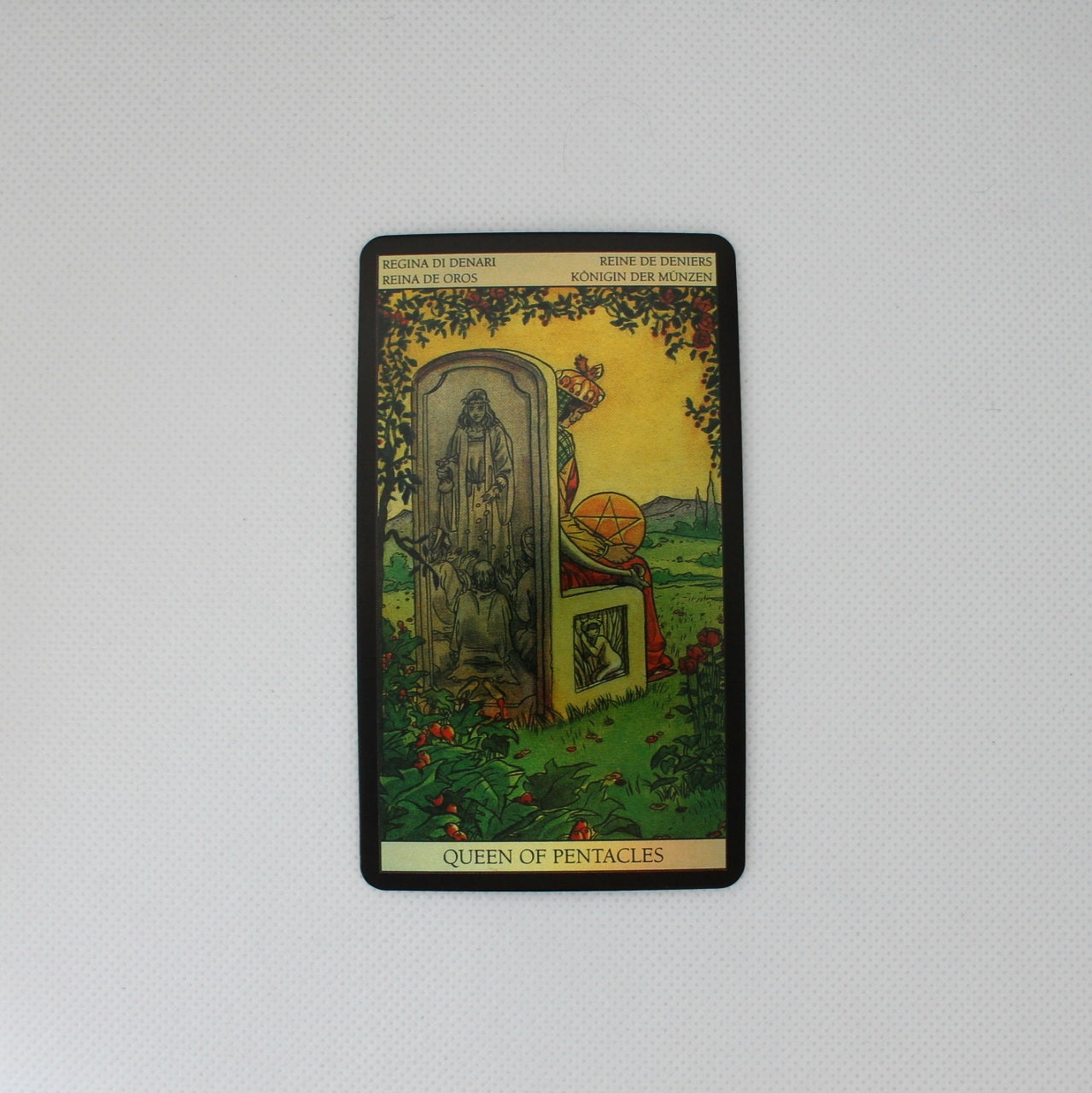 Karta tarota „Queen of Pentacles” przedstawiająca królową na tronie, z widokiem na krajobraz w tle.