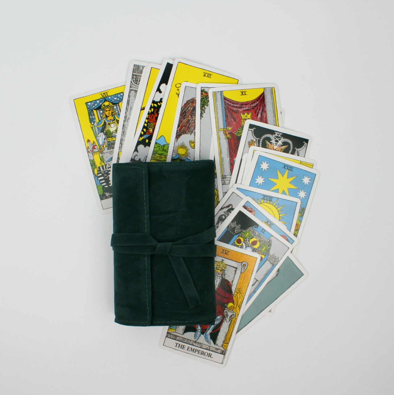 Ciemnozielony aksamitny futerał na karty tarota z wiązaniem, otoczony rozłożonymi kolorowymi kartami tarota na jasnym tle