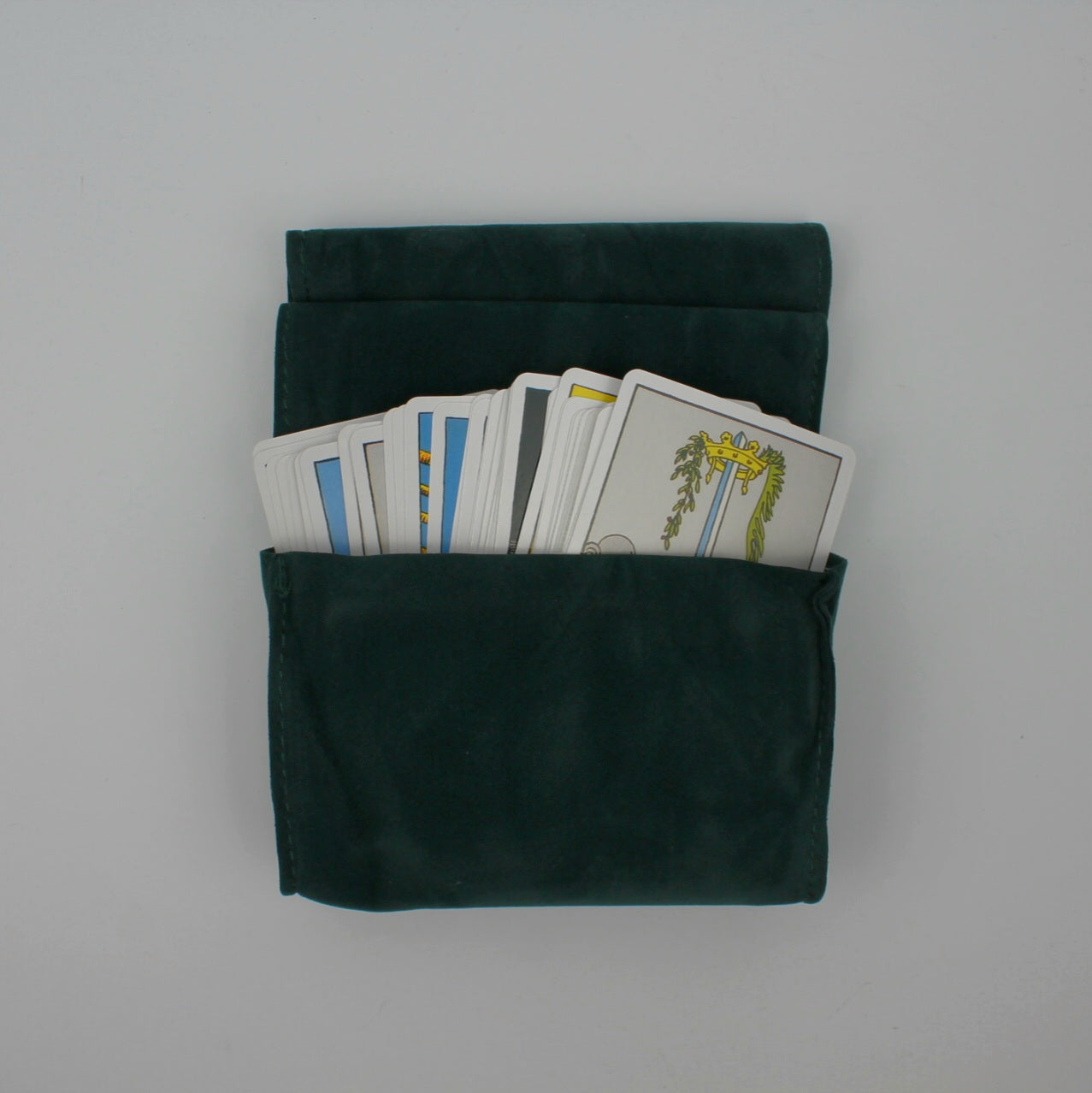 Widok z góry na ciemnozielony aksamitny futerał z kartami tarota częściowo wystającymi z wnętrza