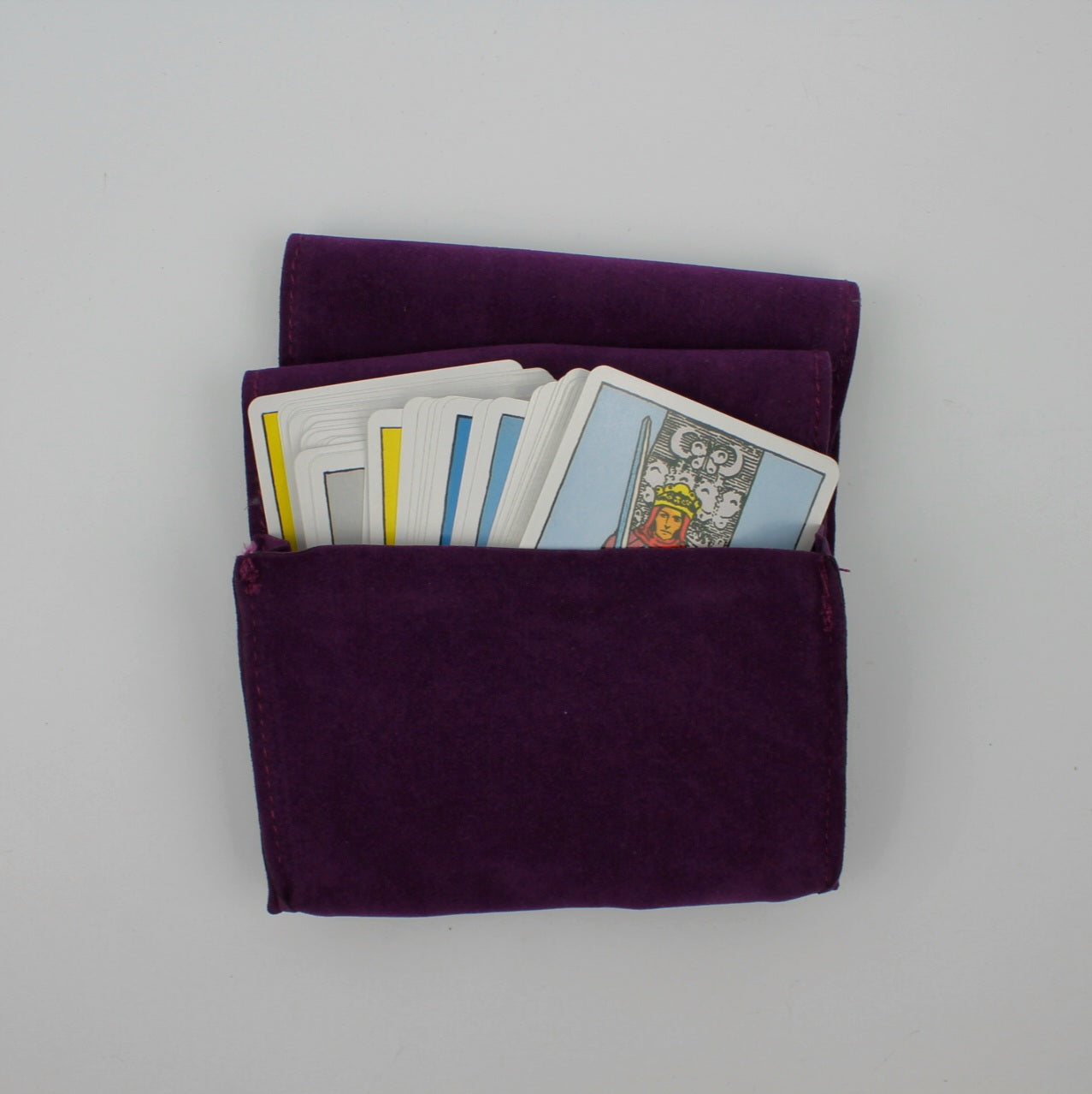 Widok z góry na fioletowy aksamitny woreczek z kartami tarota częściowo wystającymi z wewnątrz
