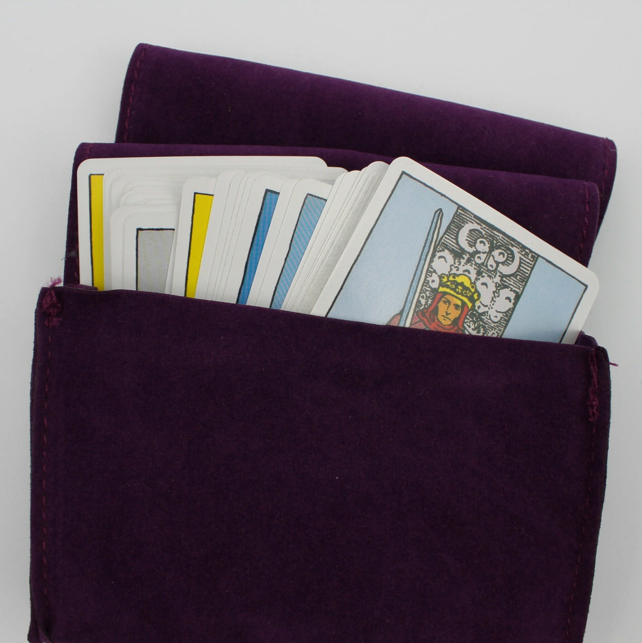 Fioletowy aksamitny futerał na karty tarota z widocznymi kartami wewnątrz, fotografowany z góry