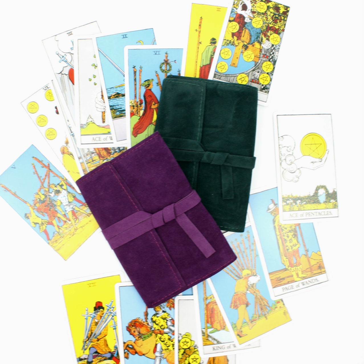 Artystyczna kompozycja z góry przedstawiająca dwa aksamitne futerały (zielony i fioletowy) otoczone rozproszonymi kolorowymi kartami tarota
