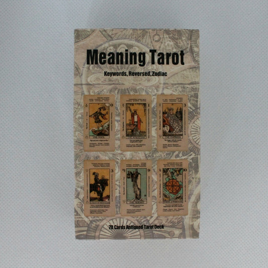 Zdjęcie przedstawia opakowanie talii kart tarota zatytułowanej "Meaning Tarot" z grafiką przedstawiającą sześć kart na przodzie pudełka. Na pudełku znajdują się także słowa kluczowe: "Keywords, Reversed, Zodiac". Talia składa się z 78 kart o antycznym wyglądzie.